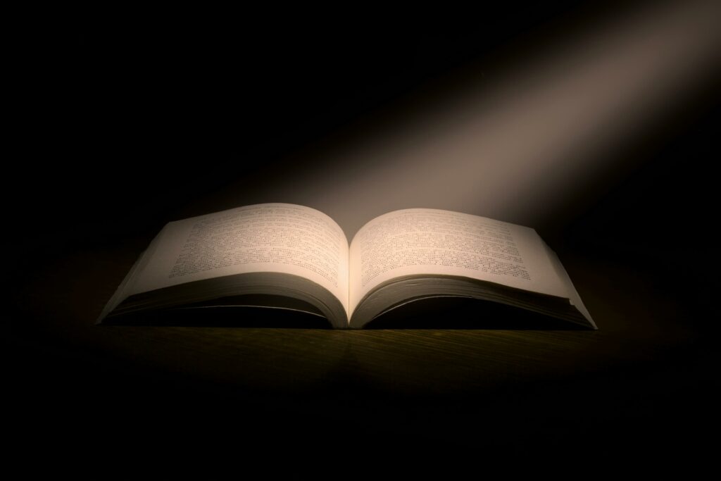 Open book with a ray of light shining down on it.
