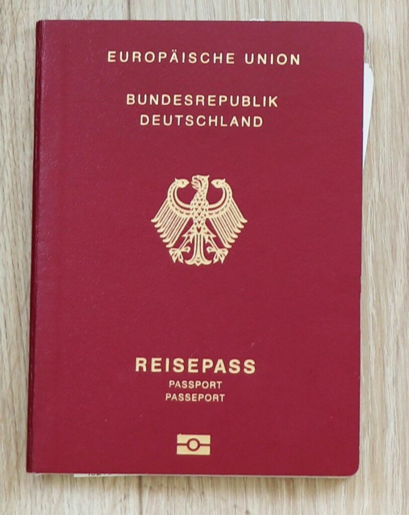 Photograph of the front cover of a passport of the Federal Republic of Germany, dark red and gold-embossed, featuring the Federal Eagle and the electronic passport logo. The writing reads “Europäische Union, Bundesrepublik Deutschland” at the top and the word “Passport” in German, English, and French at the Bottom.