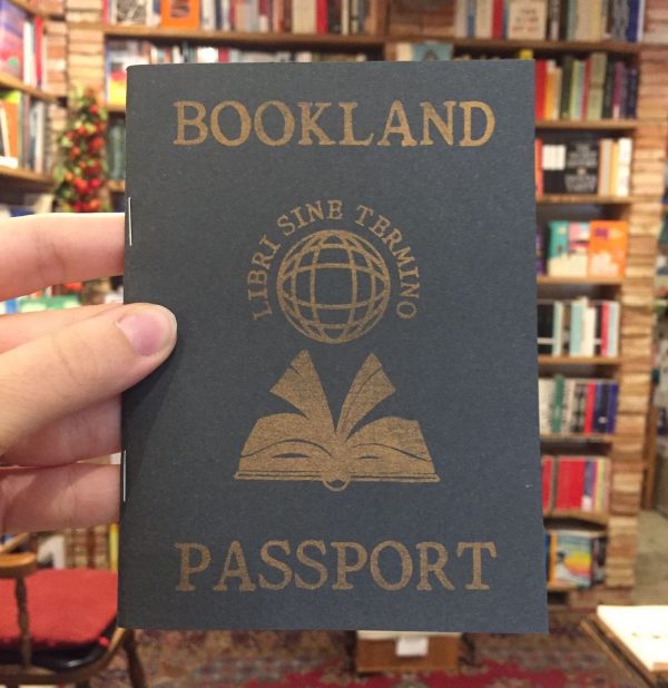 Front Cover of “Bookland Passport”. A grey paper booklet, staple bound and with golden lettering. In addition to the title, the cover shows an open book above which floats a stylized terrestrial globe surrounded by the slogan “LIBRI SINE TERMINO”