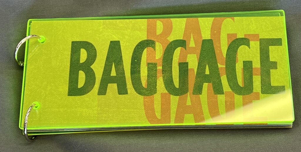 Neon green plexiglass cover of long rectangular artists’ books ‘Baggage,’ fastened at the short end with two binder rings. The title of ‘Baggage’ is also visible as screenprinted on the first page of the book, through the cover.
